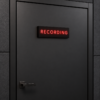 Black resin recording sign with thin red illuminated lettering